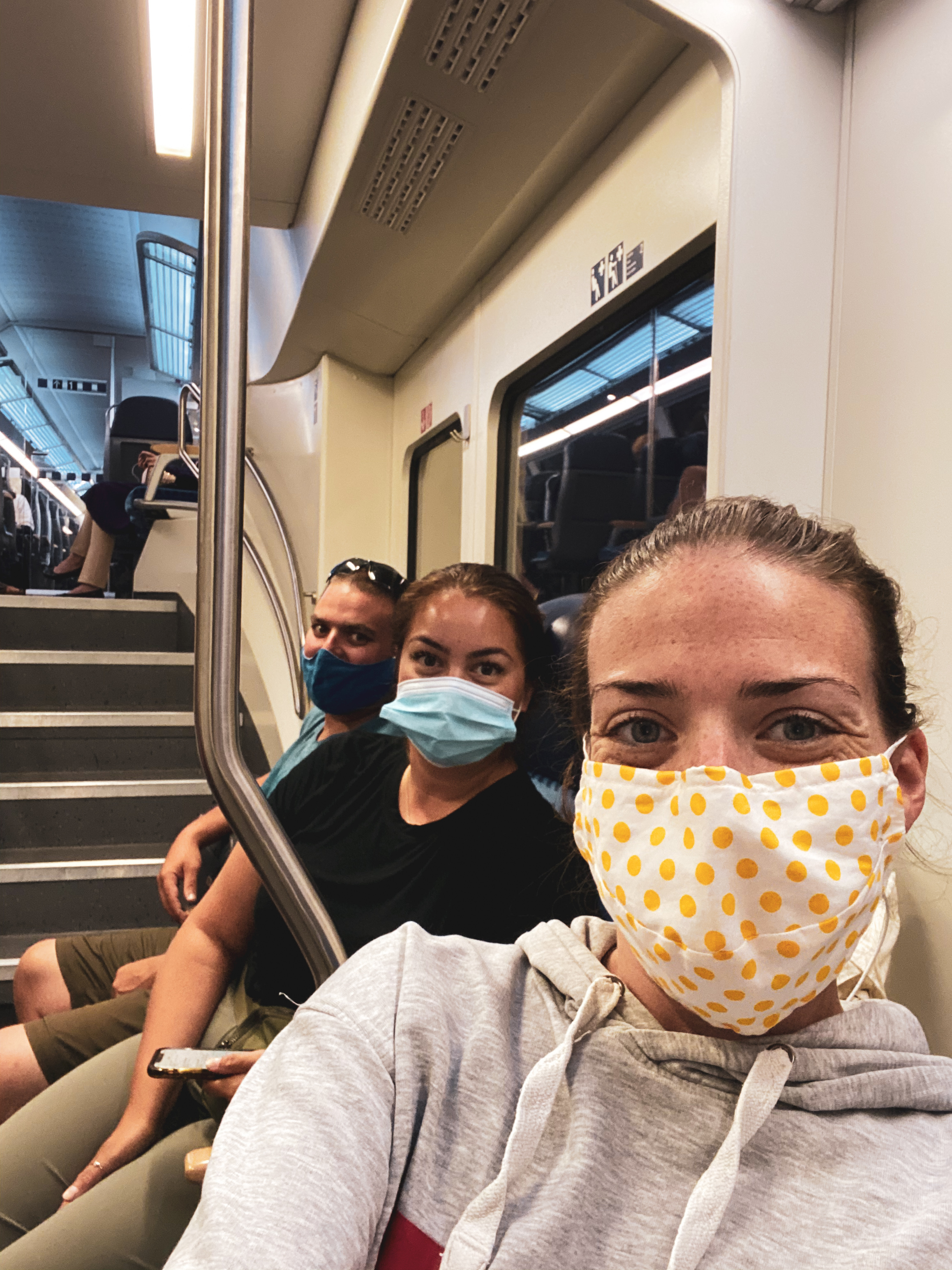 Travel during COVID 19. Three people wearing masks on a train while travelling