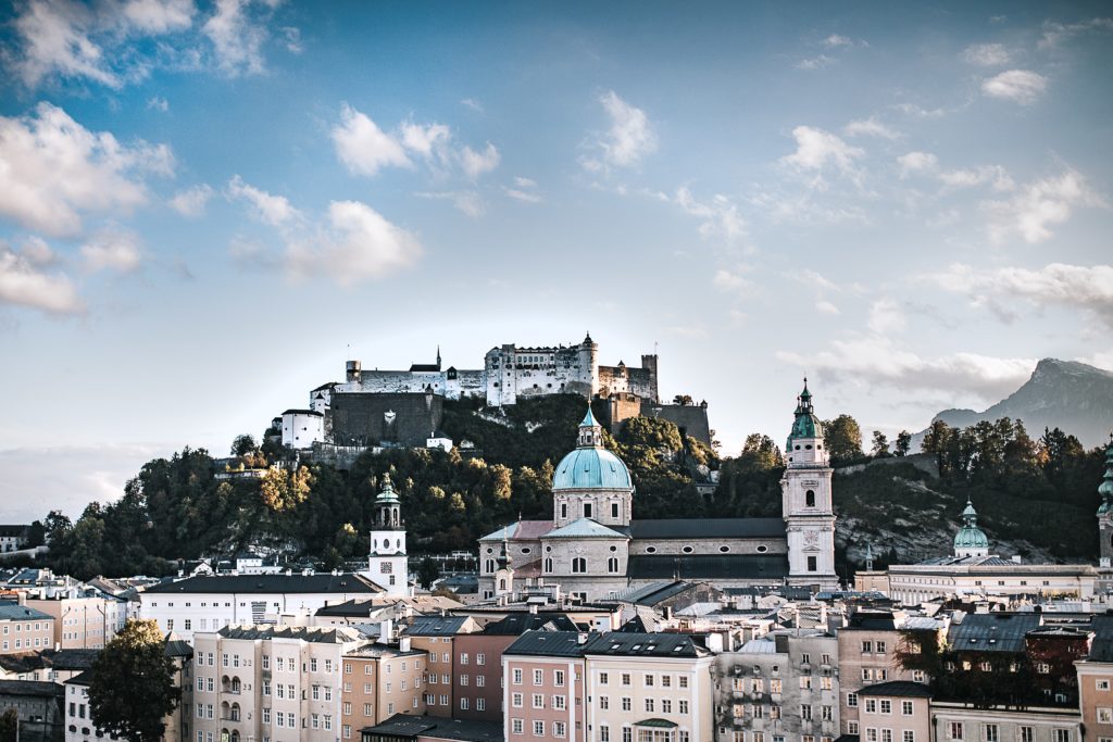 center of salzburg, white building and castle on top of a hill